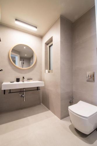 a bathroom with a toilet and a sink and a mirror at blue symphony suites and apartments in Nikiana