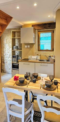 - une cuisine avec une table en bois et des chaises blanches dans l'établissement La petite maison bleue, à Mouret