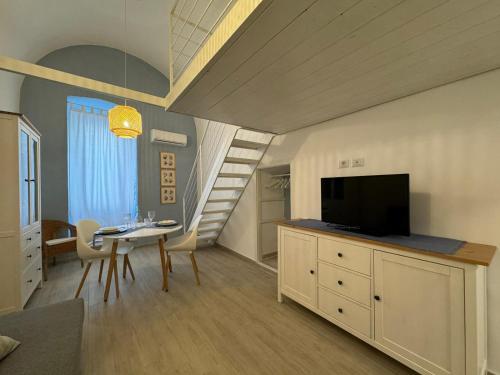a living room with a table and a television and a staircase at la casa di NU in Bisceglie