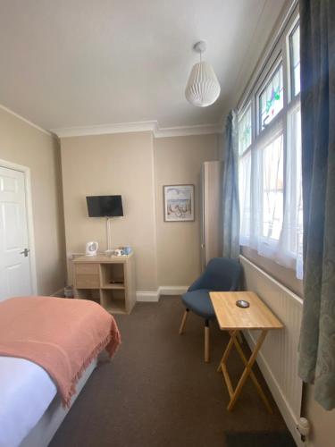 a bedroom with a bed and a desk and a window at Seren Villa in Llandudno