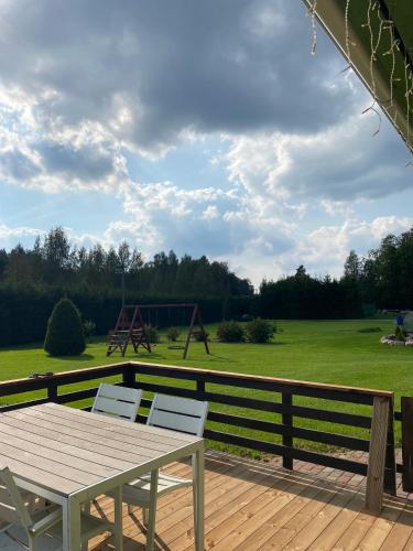 a wooden deck with a picnic table and a playground at Oraveski talu in Lodja