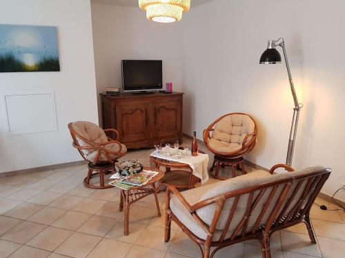 a living room with chairs and a table and a tv at Gîte à Saint André des Eaux in Saint-André-des-Eaux