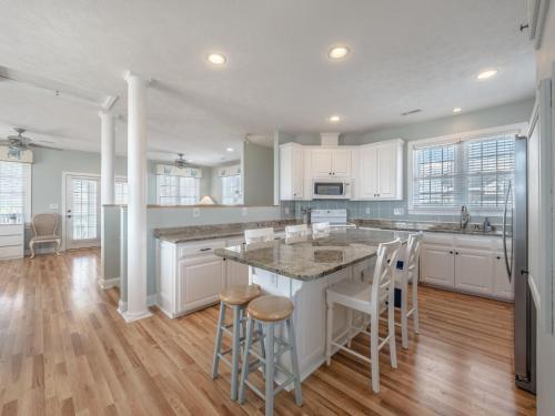 a kitchen with white cabinets and a large island with bar stools at Skippers Hideout in North Topsail Beach