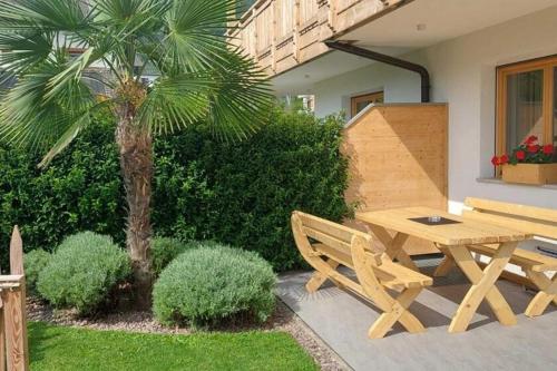 a wooden picnic table and bench next to a palm tree at Chalet Schaller in Tesimo