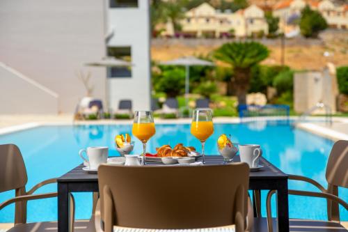 una mesa con dos vasos de zumo de naranja y un plato de comida en Celestial Lindos Suites, en Lindos