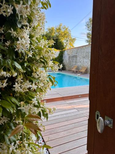 - une vue sur la piscine depuis une porte fleurie dans l'établissement LE DOMAINE DE FERRAT, à Mirambeau