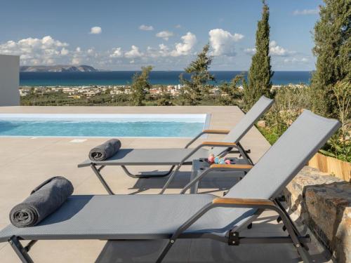 a patio with two chairs and a table next to a pool at Terra Della Salvia in Crete in Gournes