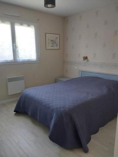 une chambre avec un lit bleu et deux fenêtres dans l'établissement Petite maison plain pied Clohars, à Clohars-Carnoët