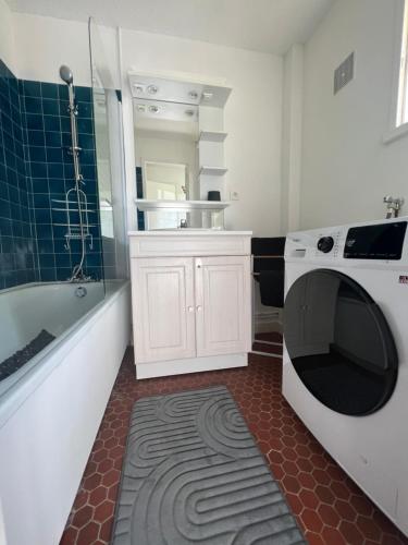 une salle de bain avec un lave-linge et une baignoire dans l'établissement Studio Cosy, à Ploemel