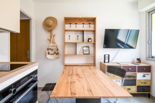 Il comprend une cuisine avec une table en bois et une télévision. dans l'établissement STUDIO COSY - Tout Confort, à Rodez