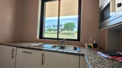 a kitchen counter with a sink and a window at Apartamento com terraços privativos em resort de luxo, By QoZzy in Alvor