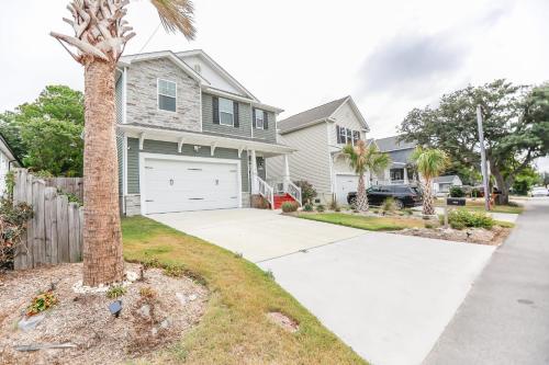 ein Haus mit einer Palme vor einer Einfahrt in der Unterkunft Sojourn Palm Tree Family Oasis 4 BR in North Camellia Acres