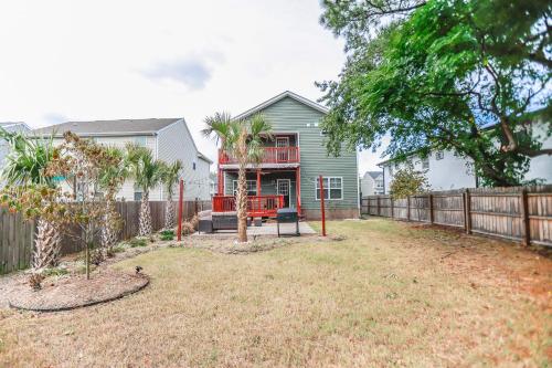 ein Haus mit einem Zaun und einem Hof in der Unterkunft Sojourn Palm Tree Family Oasis 4 BR in North Camellia Acres