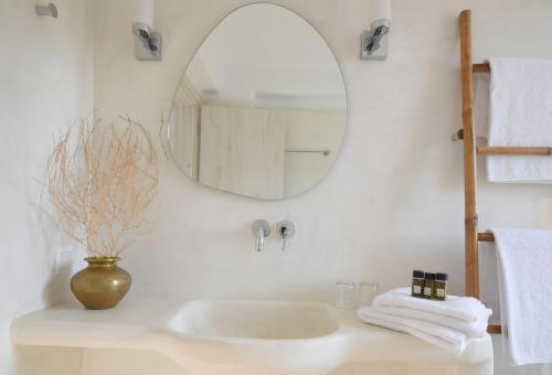 a white bathroom with a sink and a mirror at Tinos Portraits Ballos in Agios Romanos