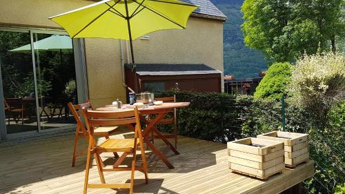 une table et des chaises avec un parasol jaune sur une terrasse dans l'établissement Le chalet de Luz avec terrasse & vue sur la vallée, à Luz-Saint-Sauveur
