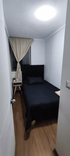 Un dormitorio con una cama negra y una ventana. en Departamento Parque O'Higgins, en Santiago