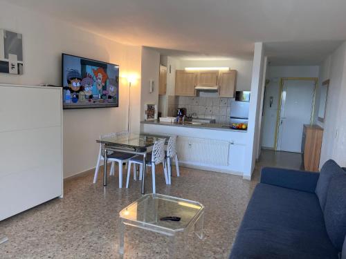 un salon avec un canapé et une table et une cuisine dans l'établissement Apparemment vue mer avec parking, à Fréjus