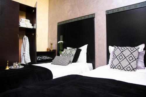 two beds with black and white pillows in a room at Hotel Vents Des Iles in Essaouira