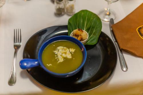 a black plate with a bowl of soup and a green leaf at Hotel Vents Des Iles in Essaouira