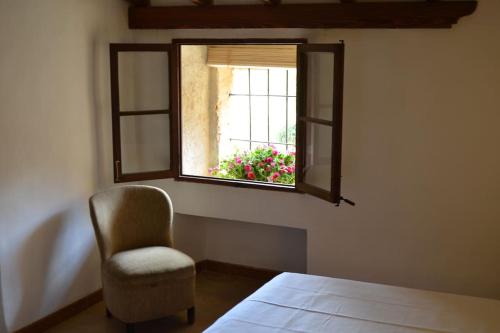 a bedroom with a chair and a window with a flower at Bonita casa de campo típica Mallorquina in Sant Jordi