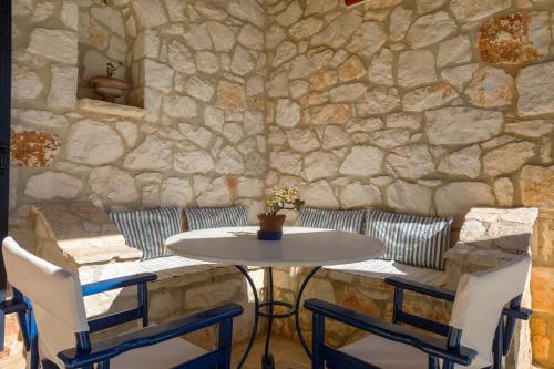 a table and two chairs and a stone wall at Aresti Mountain Resort in Agios Leon