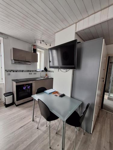 une cuisine avec une table et deux chaises et une télévision dans l'établissement Studio meublé rénové superbes prestations proche Hyper Centre - Résidence La Fresnaie, aux Rousses