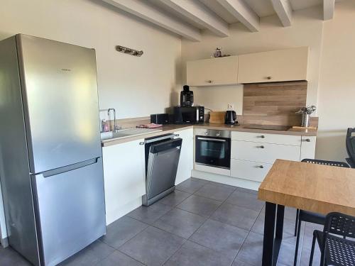 une cuisine avec des armoires blanches et un réfrigérateur en acier inoxydable dans l'établissement DUNES - Villa Patio Avec Jardin - proche Plage de la Gravière, à Soorts-Hossegor