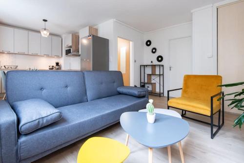 un salon avec un canapé bleu et une table dans l'établissement Appartement rénové pour 6 avec parking, à Villeurbanne