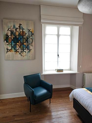 a bedroom with a blue chair and a window at L'ALBIZIA in Libin