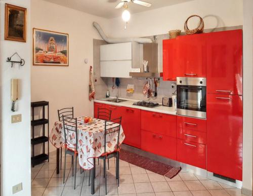 une cuisine avec des placards rouges et une table avec des chaises dans l'établissement 2 bedrooms apartement with sea view furnished terrace and wifi at Olbia 5 km away from the beach, à Olbia