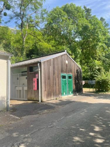 un bâtiment en bois avec des portes vertes à côté d'une rue dans l'établissement Camping Onlycamp le Clos Imbert, à Thouars