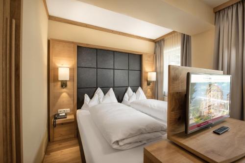 pokój hotelowy z łóżkiem i telewizorem w obiekcie Appartement Hotel Panorama-im Bademantel direkt in die Alpentherme w mieście Bad Hofgastein