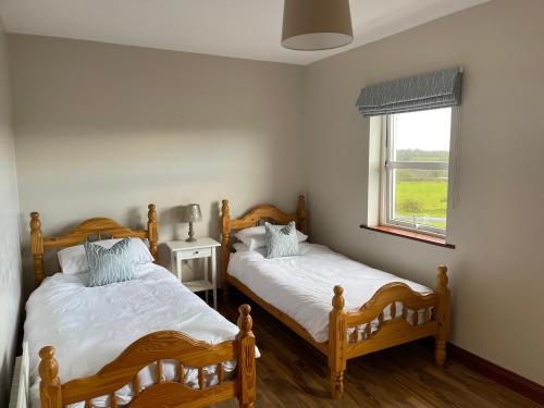 two twin beds in a bedroom with a window at Cassidy Cottages 3 Bed in Cavan
