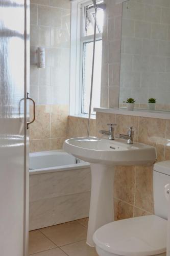 a bathroom with a sink and a tub and a toilet at Belvilla Crewe Arms Hotel in Crewe
