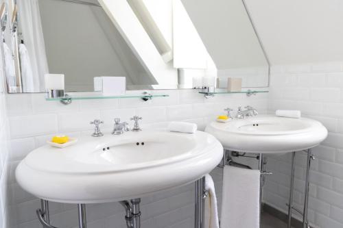une salle de bain blanche avec deux lavabos et un miroir dans l'établissement White 1921, à Saint-Tropez