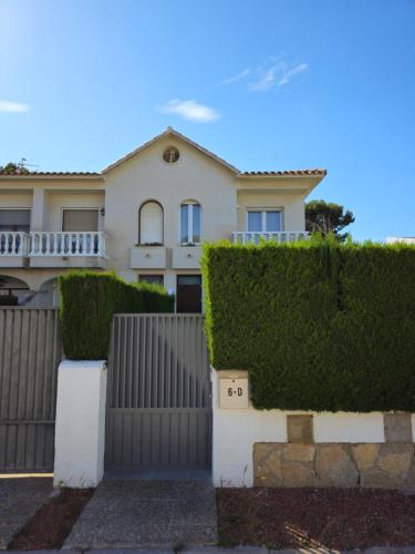 una casa blanca con una valla y arbustos en Casa Bedoll, en Miami Platja