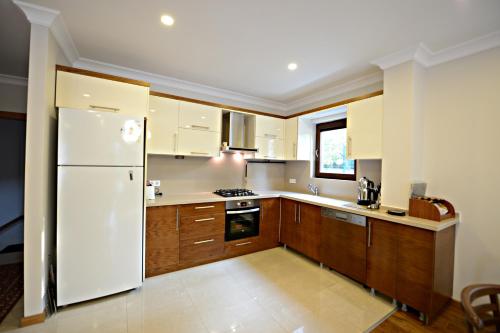 a kitchen with a white refrigerator and wooden cabinets at Guzel Evler Family Resort in Sapanca