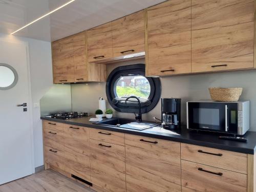a kitchen with wooden cabinets and a microwave at Hausboot Emsblick in Walchum
