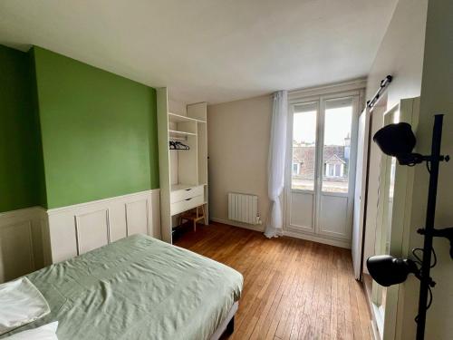 une chambre verte avec un lit et une fenêtre dans l'établissement Le Verde, à Melun