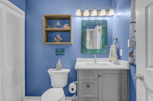 a blue bathroom with a toilet and a sink at Slow Motion #8A in Topsail Beach