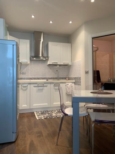 une cuisine avec des placards blancs et une table et des chaises bleues dans l'établissement Un nido a Versailles, à Versailles
