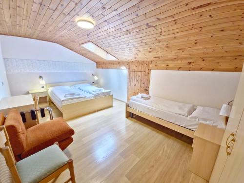 una camera con due letti, un divano e una sedia di Villa Flora by AMA Val di Fassa a Canazei