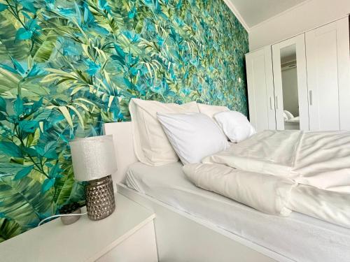 a bedroom with a bed with a tropical wallpaper at Treasure Box Apartman in Miskolc