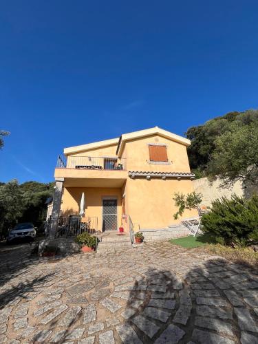 a large yellow house with a stone driveway at Venti di Vacanza - Levante & Grecale in Olbia