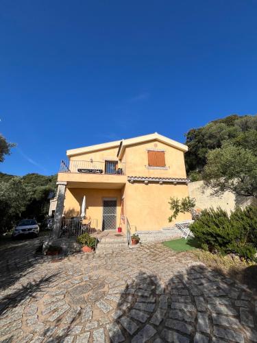 a large yellow house with a car parked in front of it at Venti di Vacanza - Levante & Grecale in Olbia