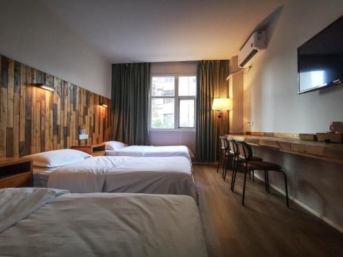 Habitación de hotel con 3 camas y TV de pantalla plana. en Sonderia Hostel & Bar - Lazybones Hostel, en Chengdú