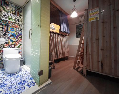 a bathroom with a toilet in a room with a wall at Sonderia Hostel & Bar - Lazybones Hostel in Chengdu