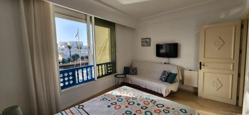 a living room with a couch and a large window at Appartement marina hammamet in Yasmine