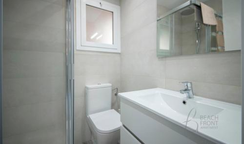 a bathroom with a toilet and a sink and a mirror at R155 - Apartamento Frente al Mar en Coma-Ruga 2 in Comarruga