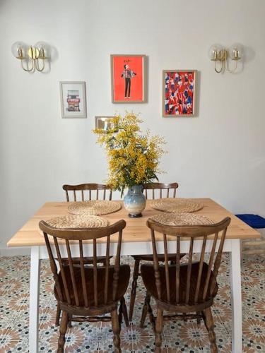 une table à manger avec des chaises et un vase de fleurs dans l'établissement Nid douillet Cosy T2 quartier haut centre-ville, à Sète